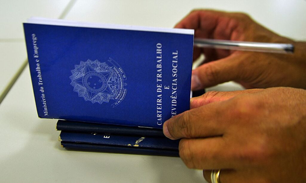 Imagem de homem assinando carteira de trabalho