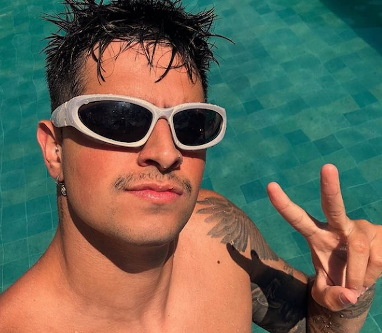 Coringa na piscina de óculos branco e fazendo sinal da paz