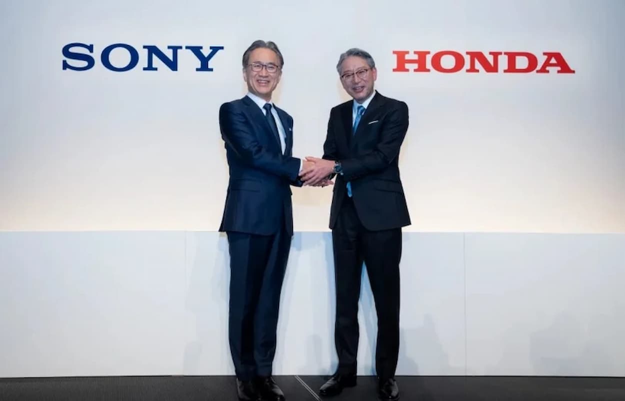 Empresários apertando as mãos em frente ao painel da Sony e Honda