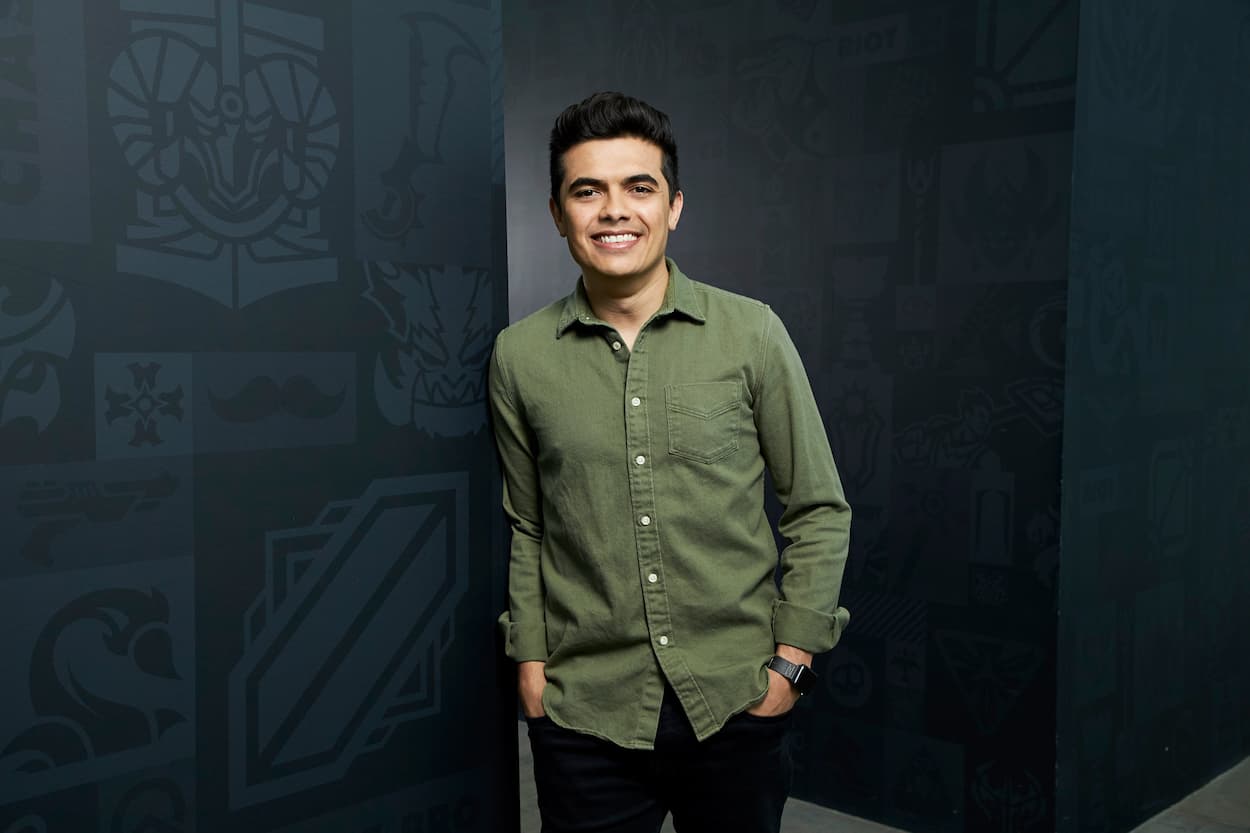 Foto Leo Faria Valorant de Líder Global Homem de camisa verde longa, sorrindo com as mãos nos bolsos da calça